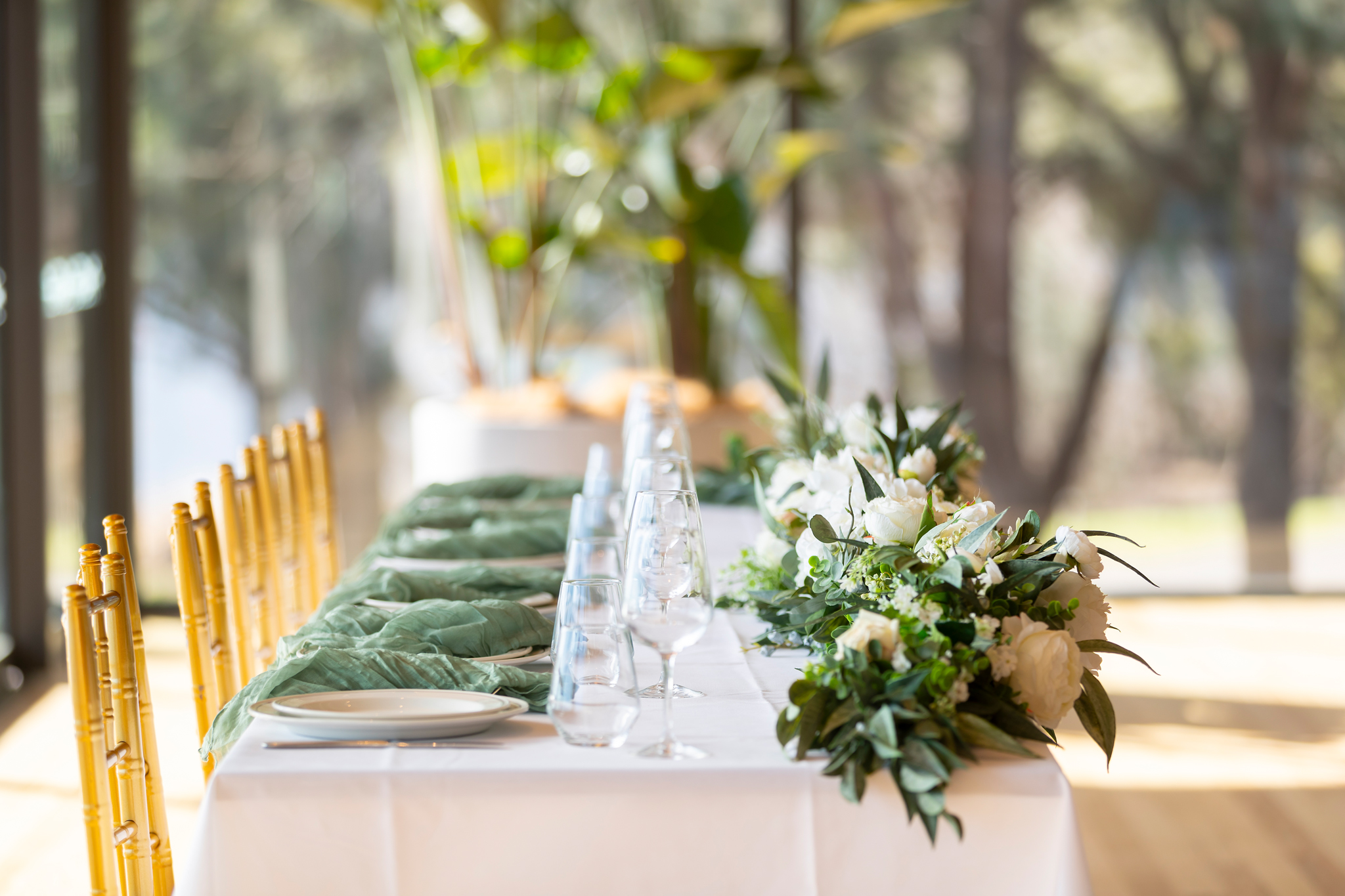 A long dining table dressed in white and sage green in the Telopea Room