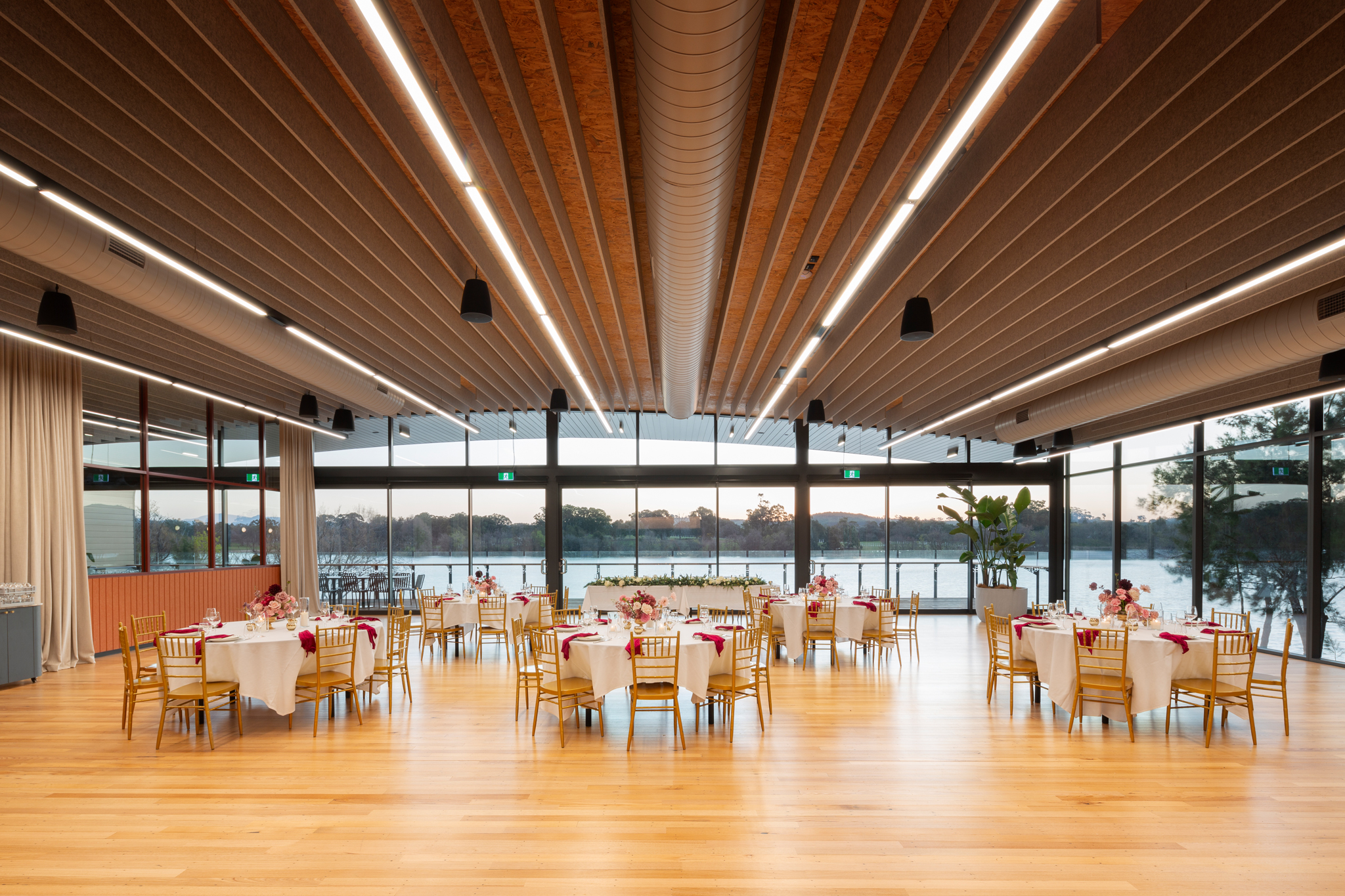 The Telopea Room set for a seated dinner, with Lake Burley Griffin filling the glass wall beyond