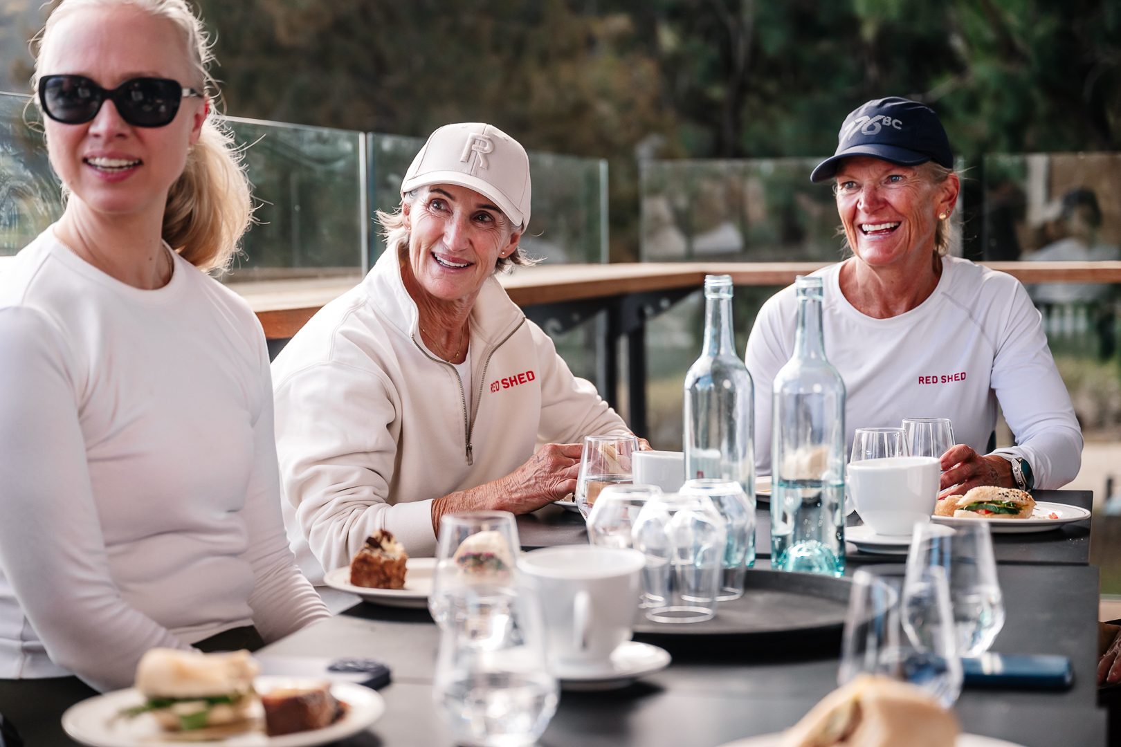 Three friends with drinks and plates on the Easy Oar deck