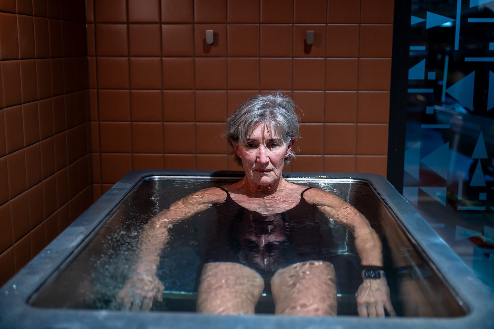 Member settling into the ice bath, arms resting on the edge