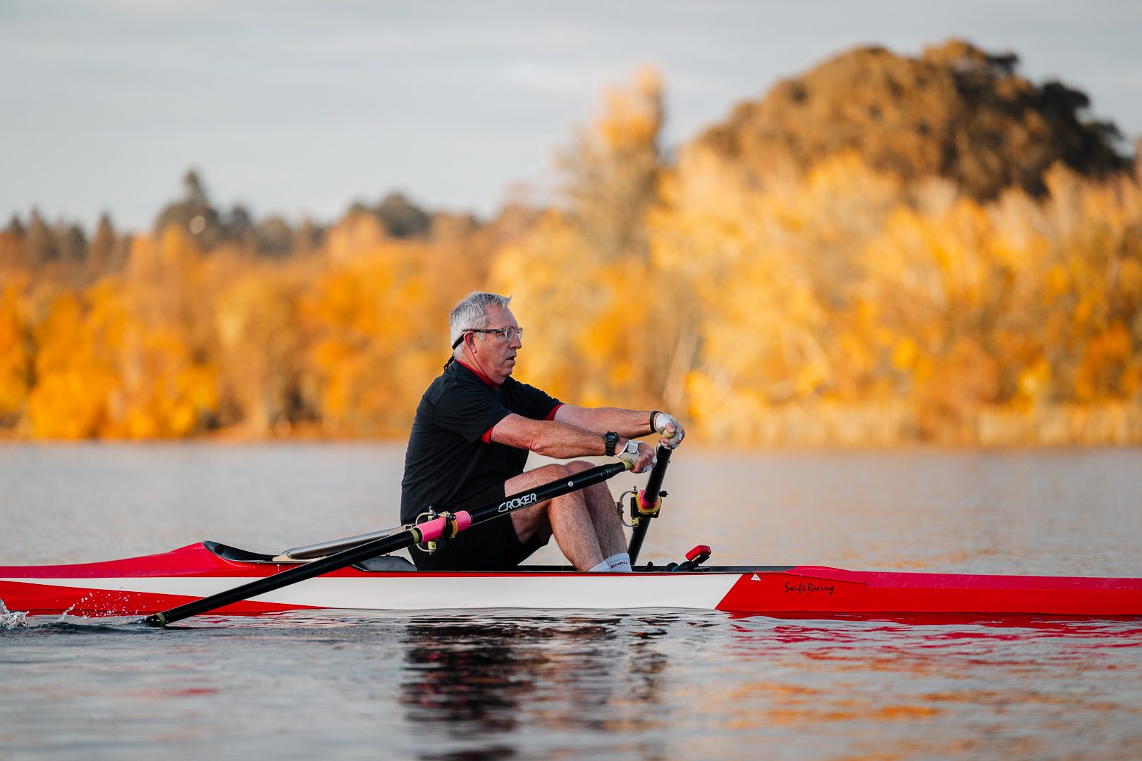 Masters rower sculling with a glowing autumn backdrop