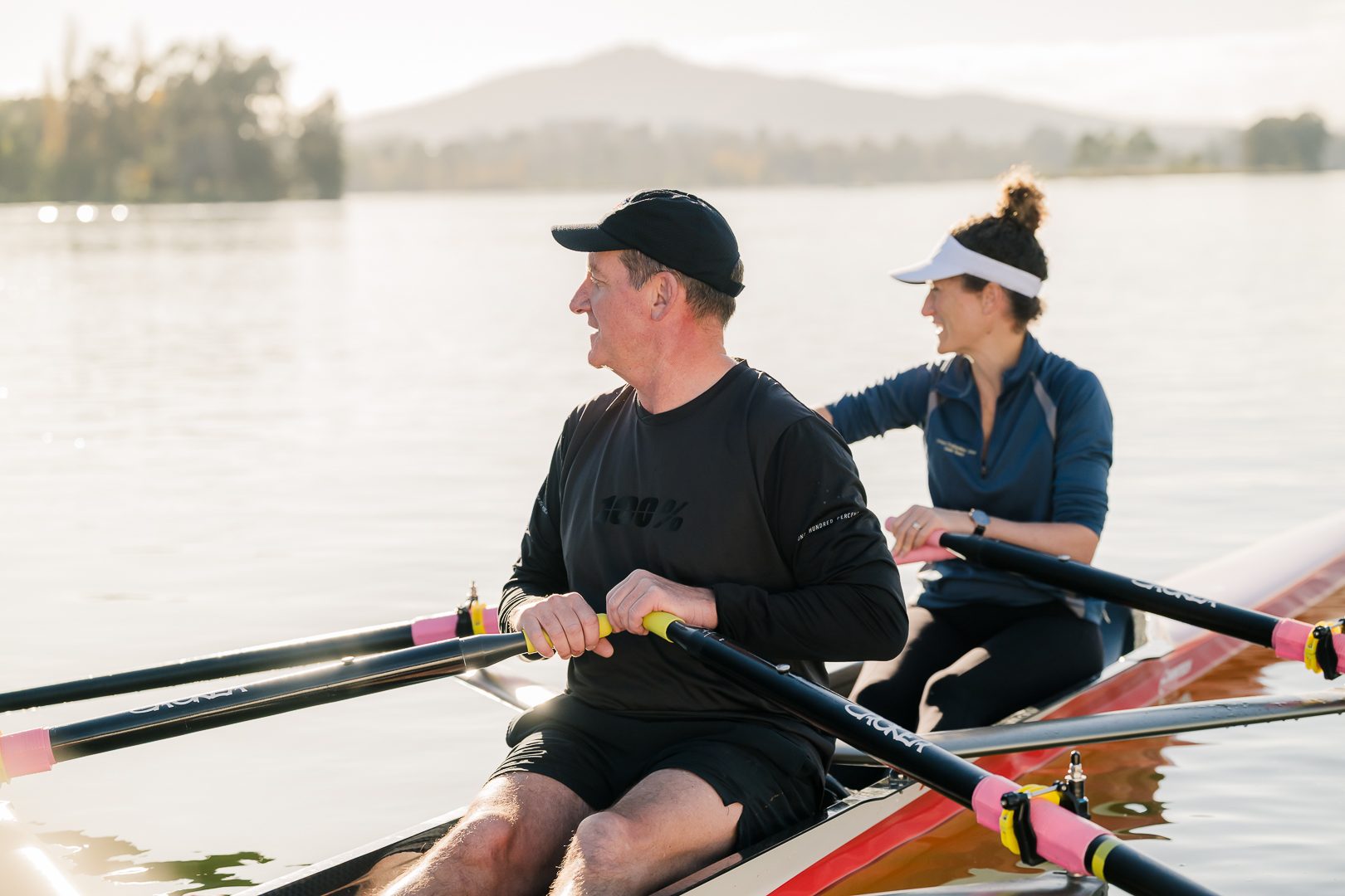Two rowers sharing a laugh on the water at dawn