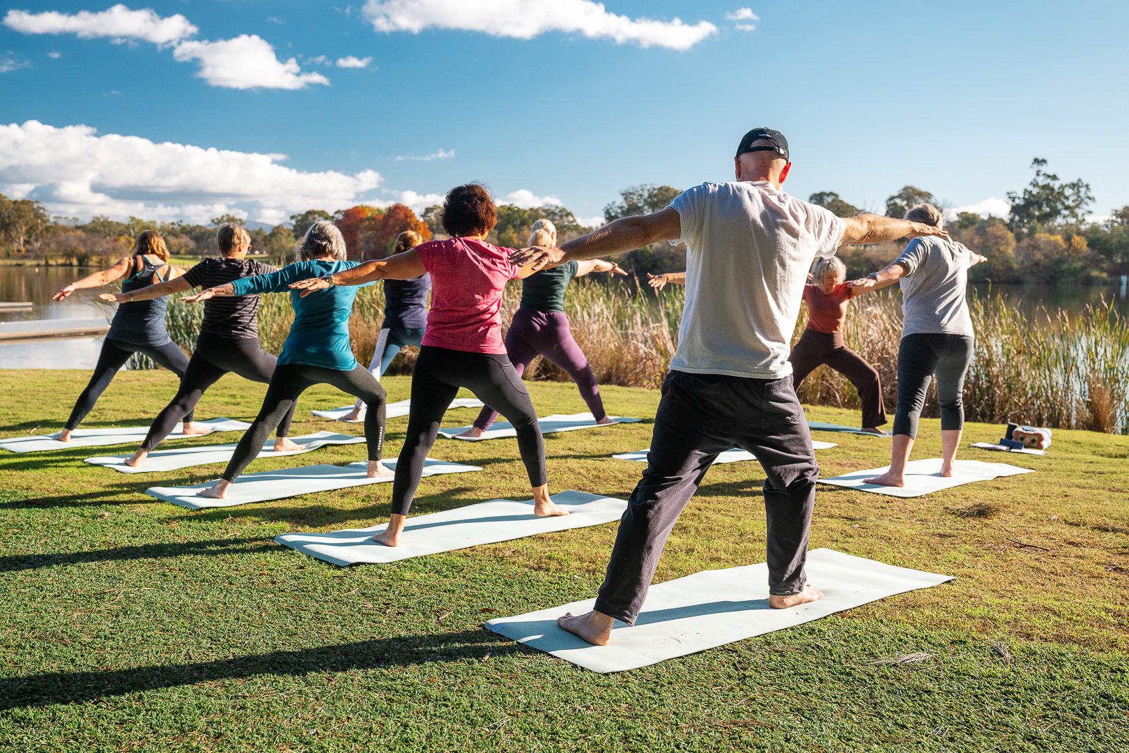 Rows of yoga participants in warrior pose on the lawn