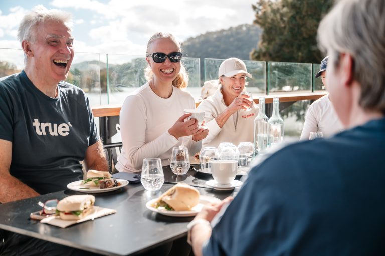 Friends laughing over lunch and coffee on the Easy Oar deck