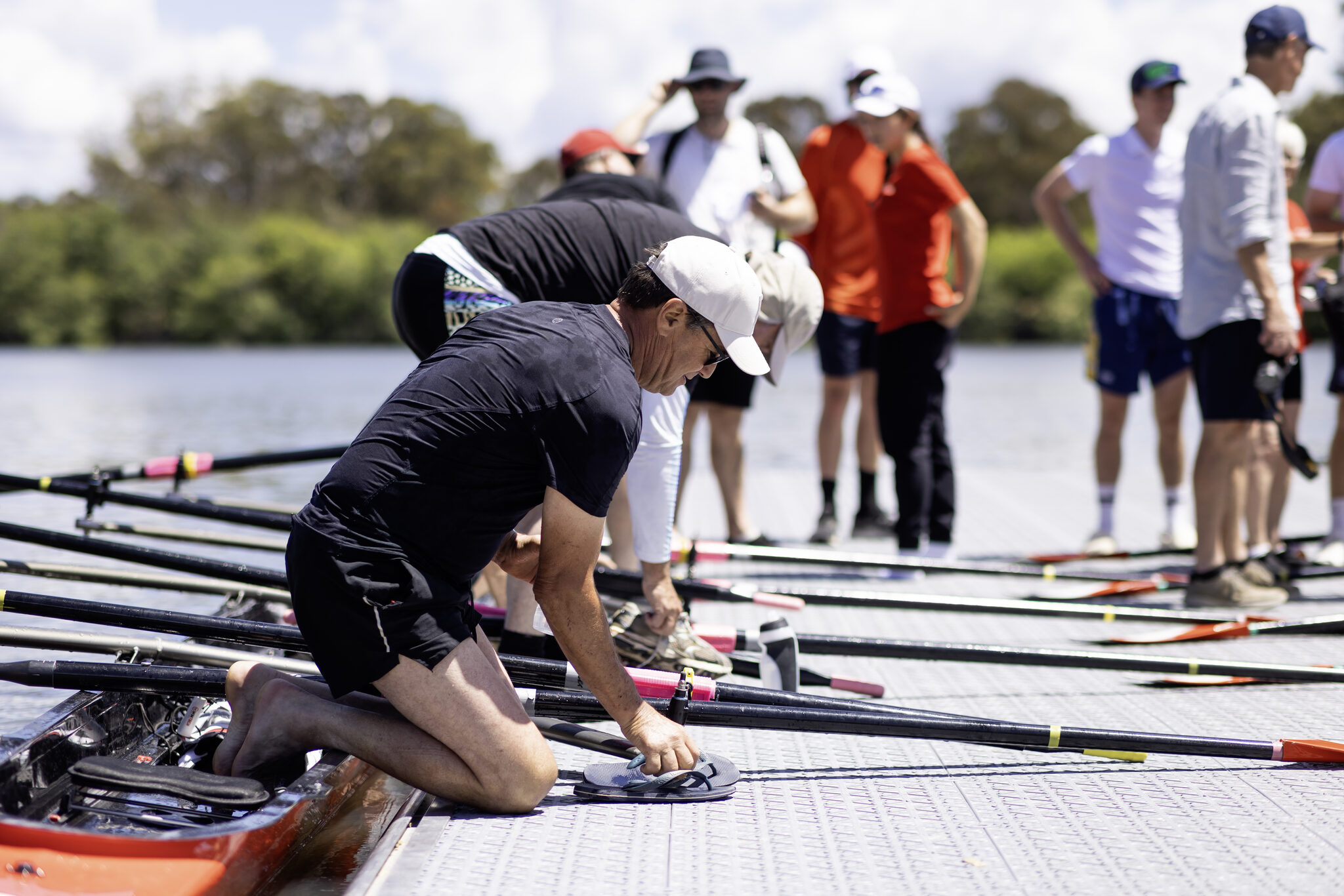 A corporate crew lifting a rowing boat off the pontoon together at Red Shed