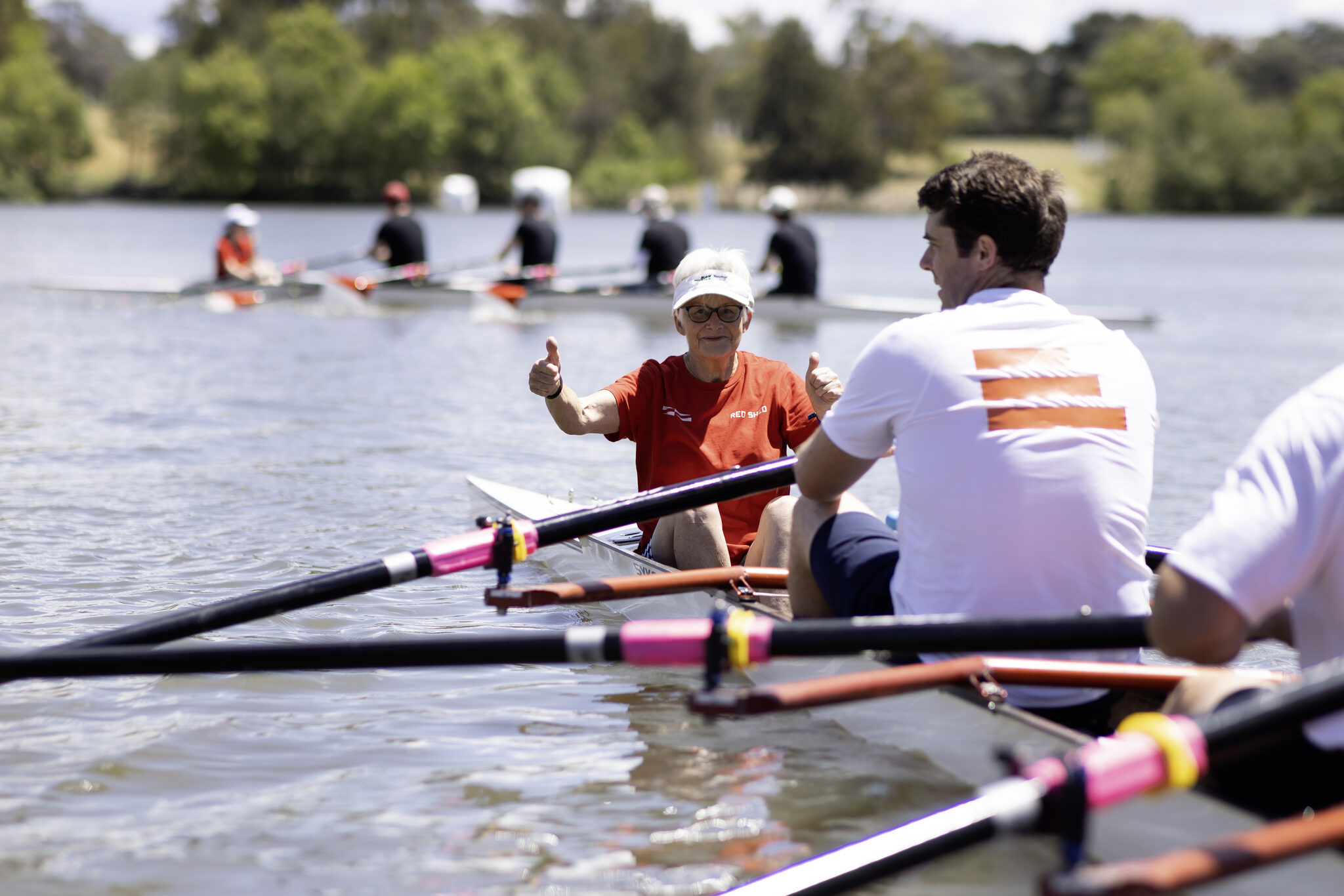 Two rowers giving a thumbs up from a boat on Lake Burley Griffin
