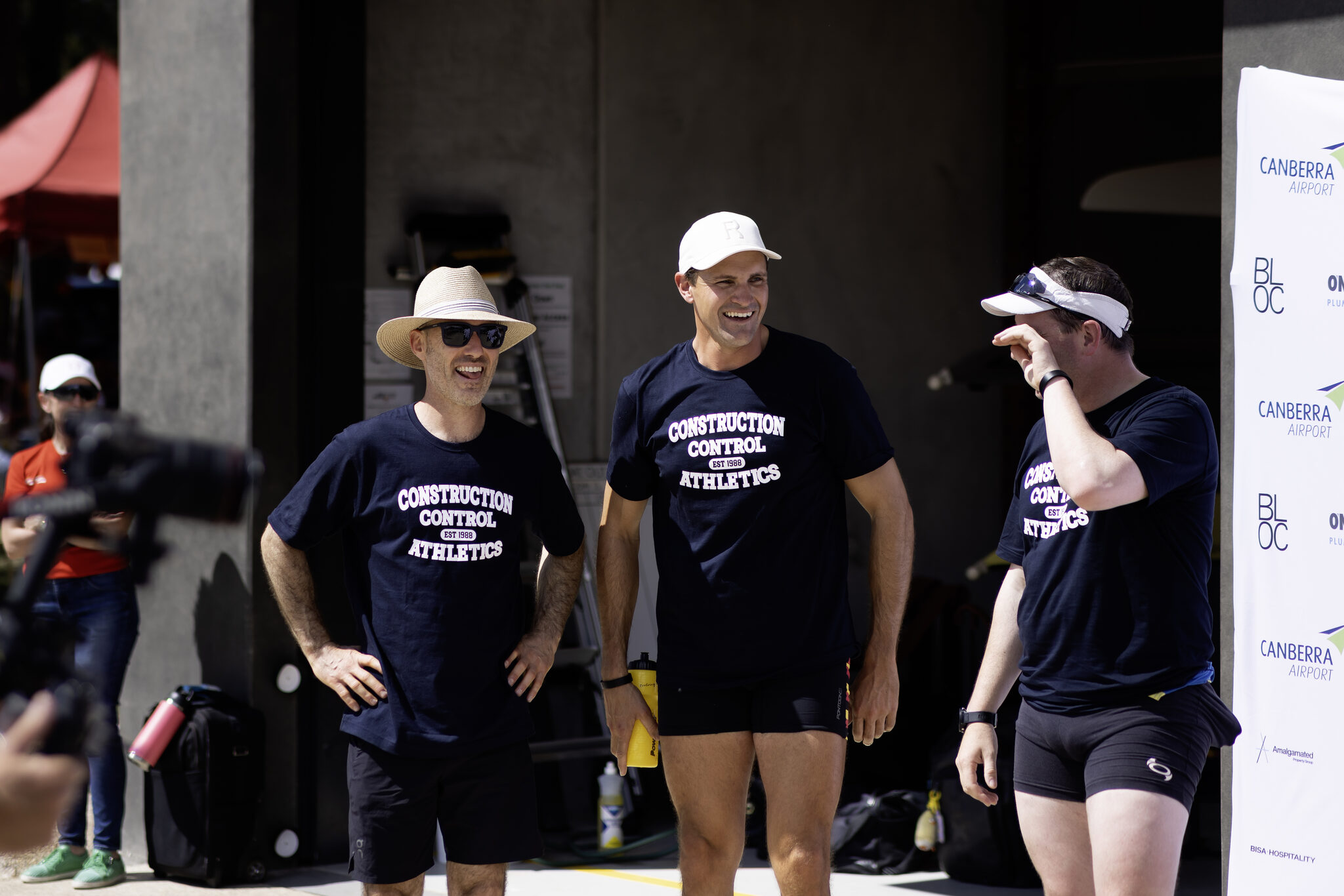 Three workmates in matching team shirts outside the Red Shed boatshed