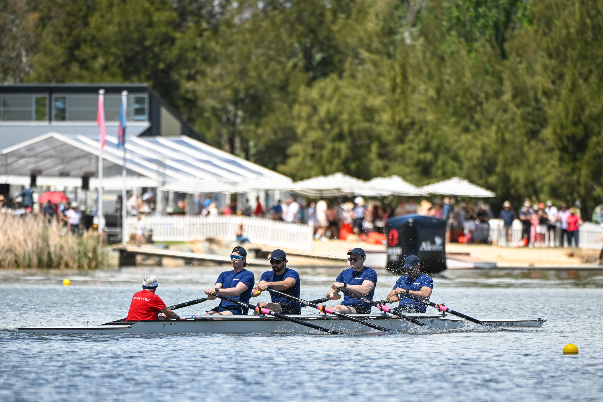 A corporate crew racing past the marquees on the Golden Oar course