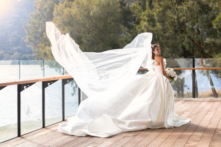 Bride on the Red Shed deck with her veil lifted in the breeze, the lake behind