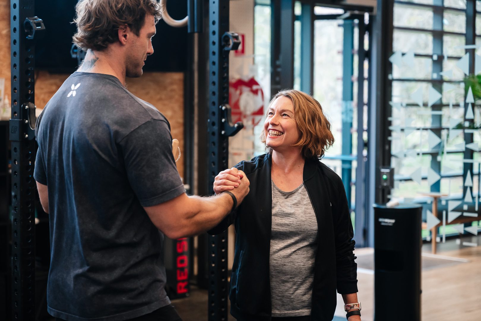 Trainer and member sharing a joyful hand clasp at RSX gym