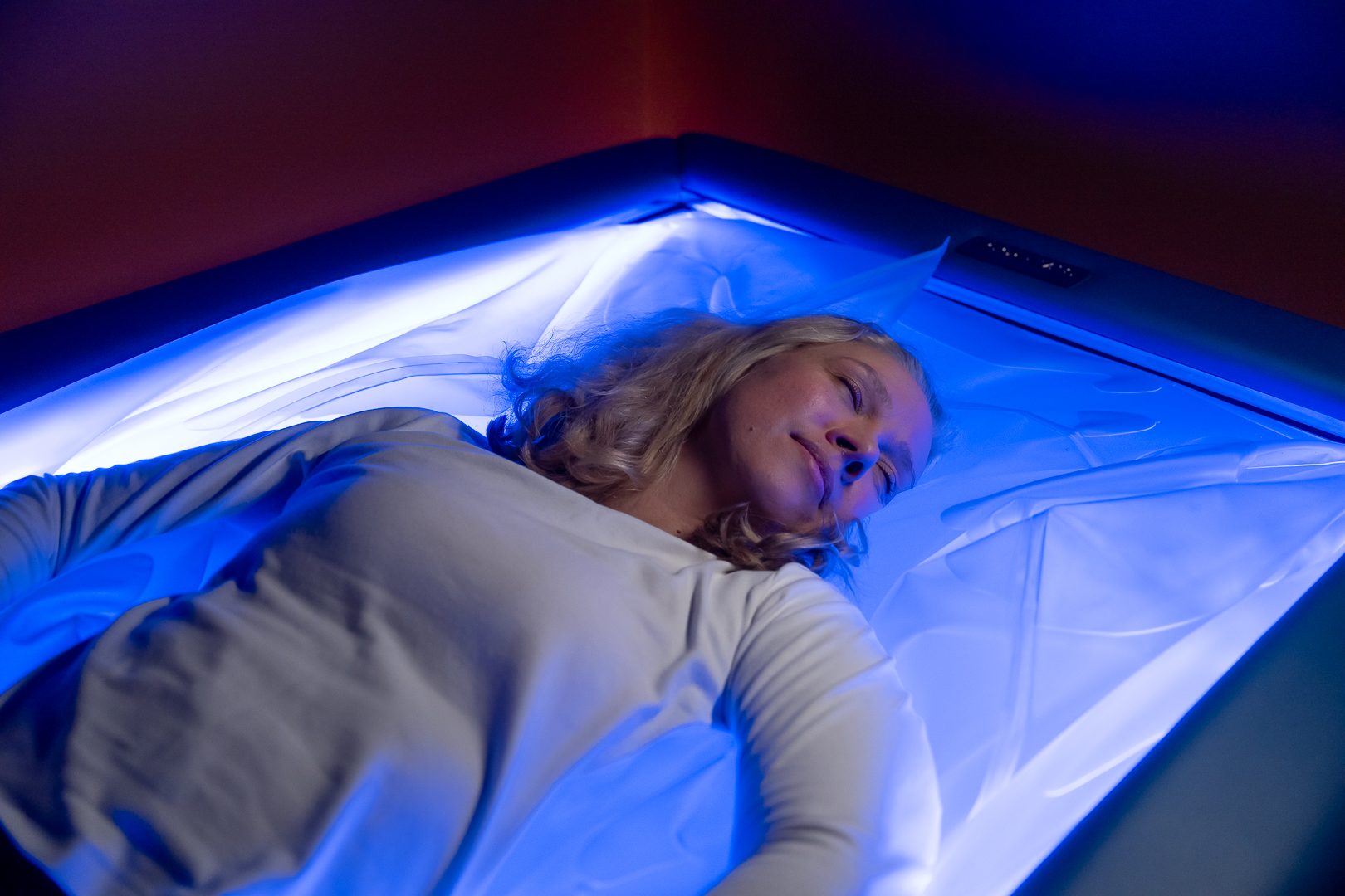 Member resting face-up on the dry float bed in soft blue light